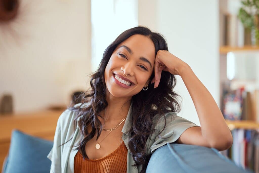 Portrait,Of,Happy,Young,Latin,Woman,Sitting,On,Sofa,At